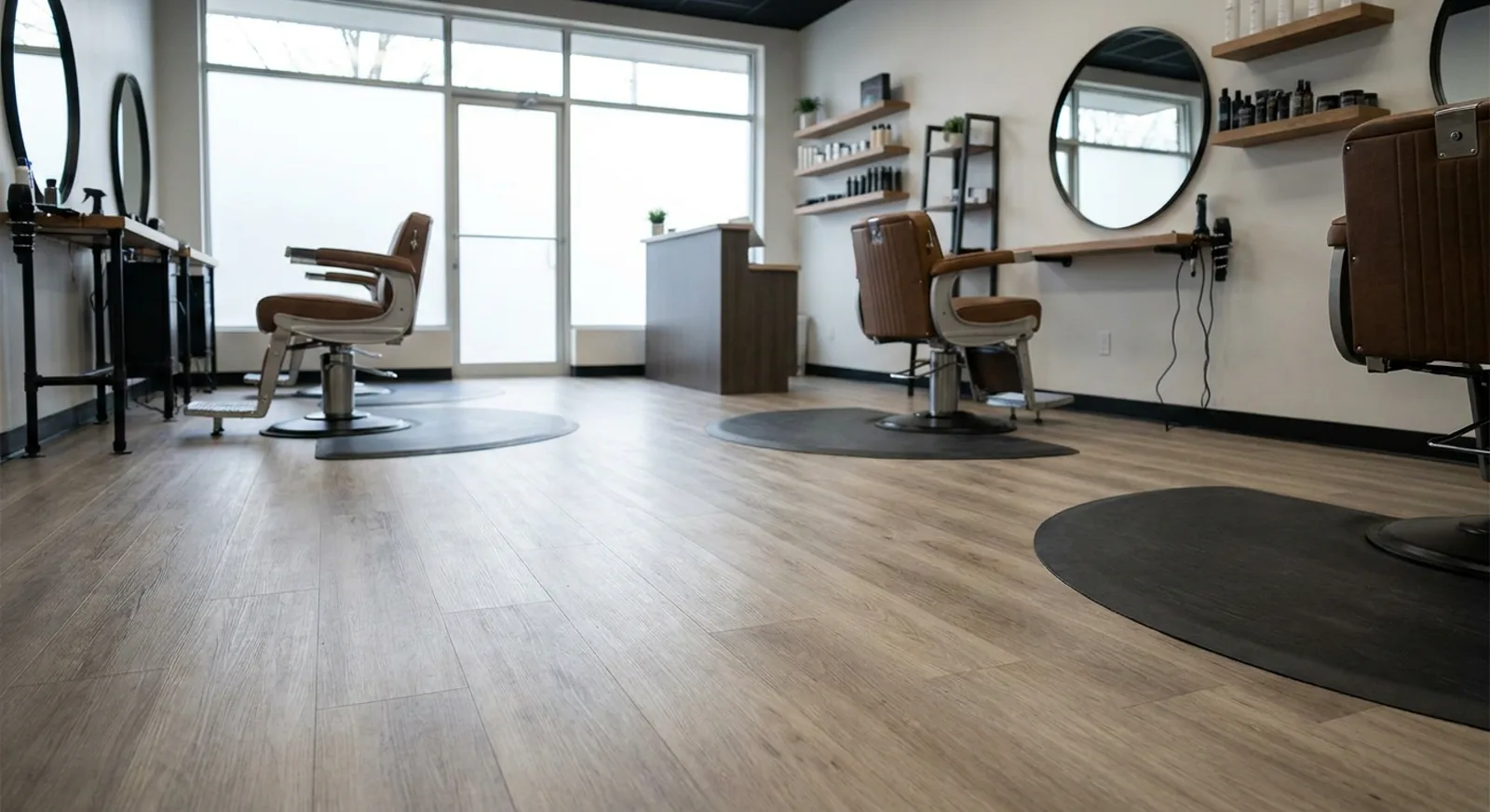 Wood-look luxury vinyl plank floor in a modern barbershop with barber chairs and mirrors, natural light