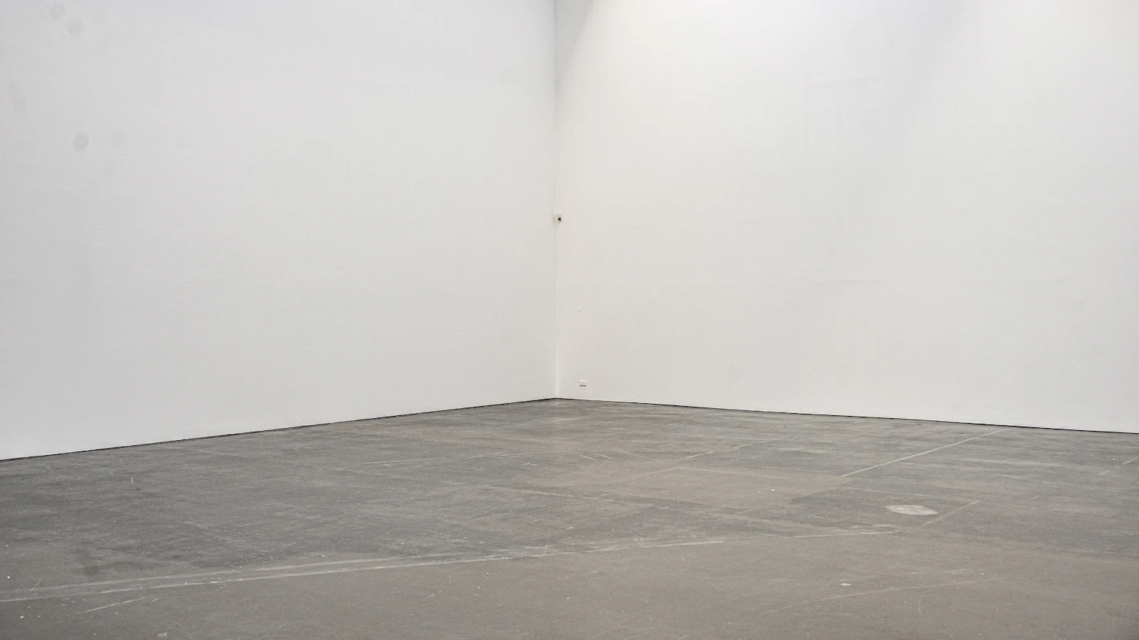 Bare concrete slab floor in an empty room with white walls, ready for flooring