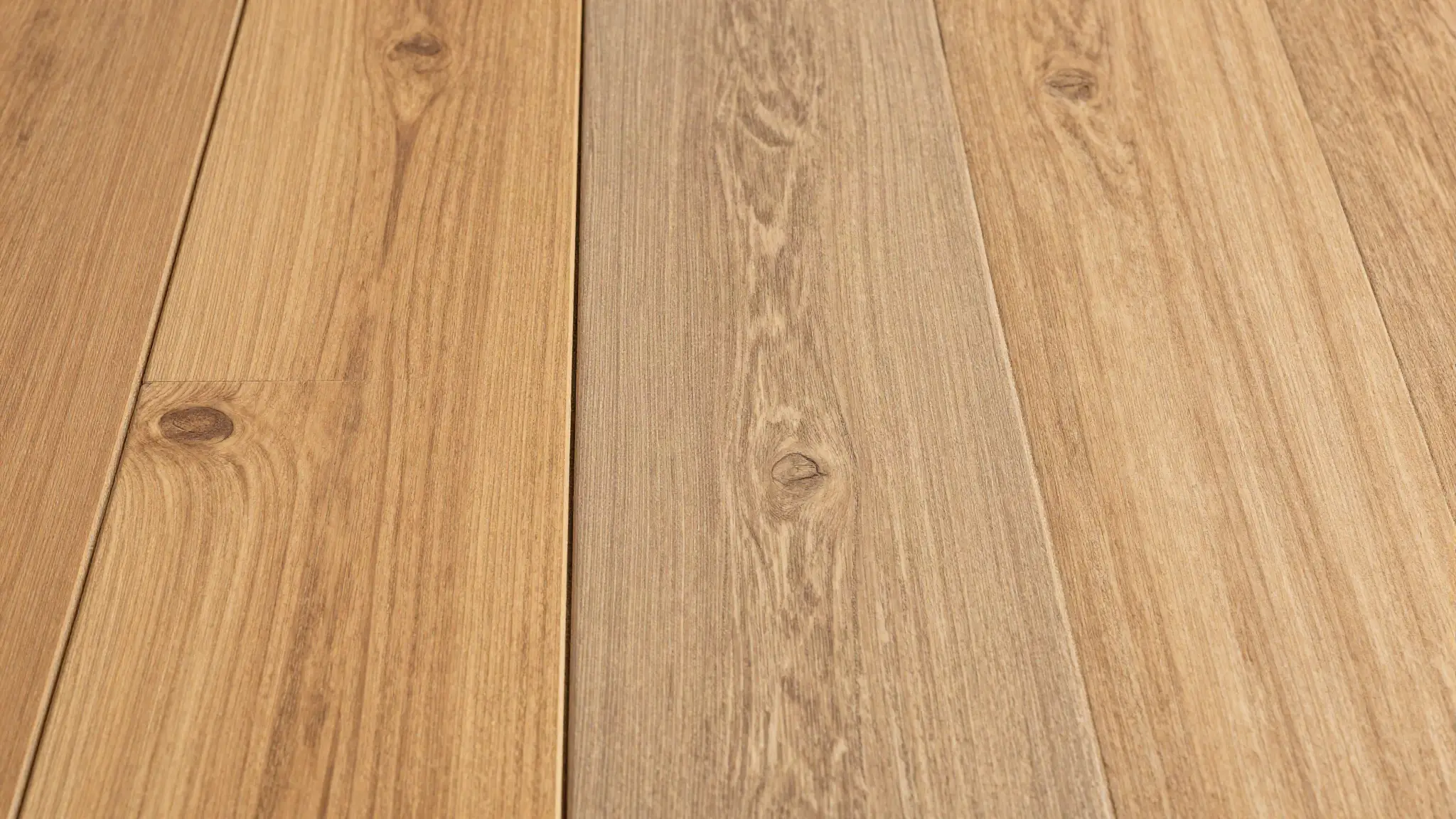Solid oak hardwood planks laid edge to edge against luxury vinyl plank flooring for comparison