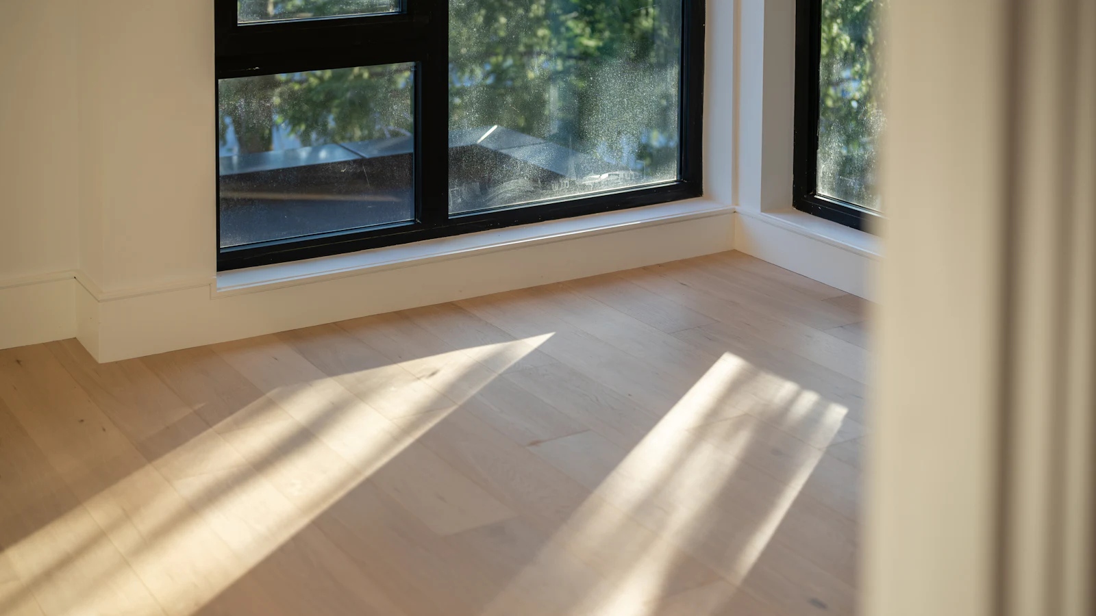 Light oak plank flooring in a bright room beside a large window