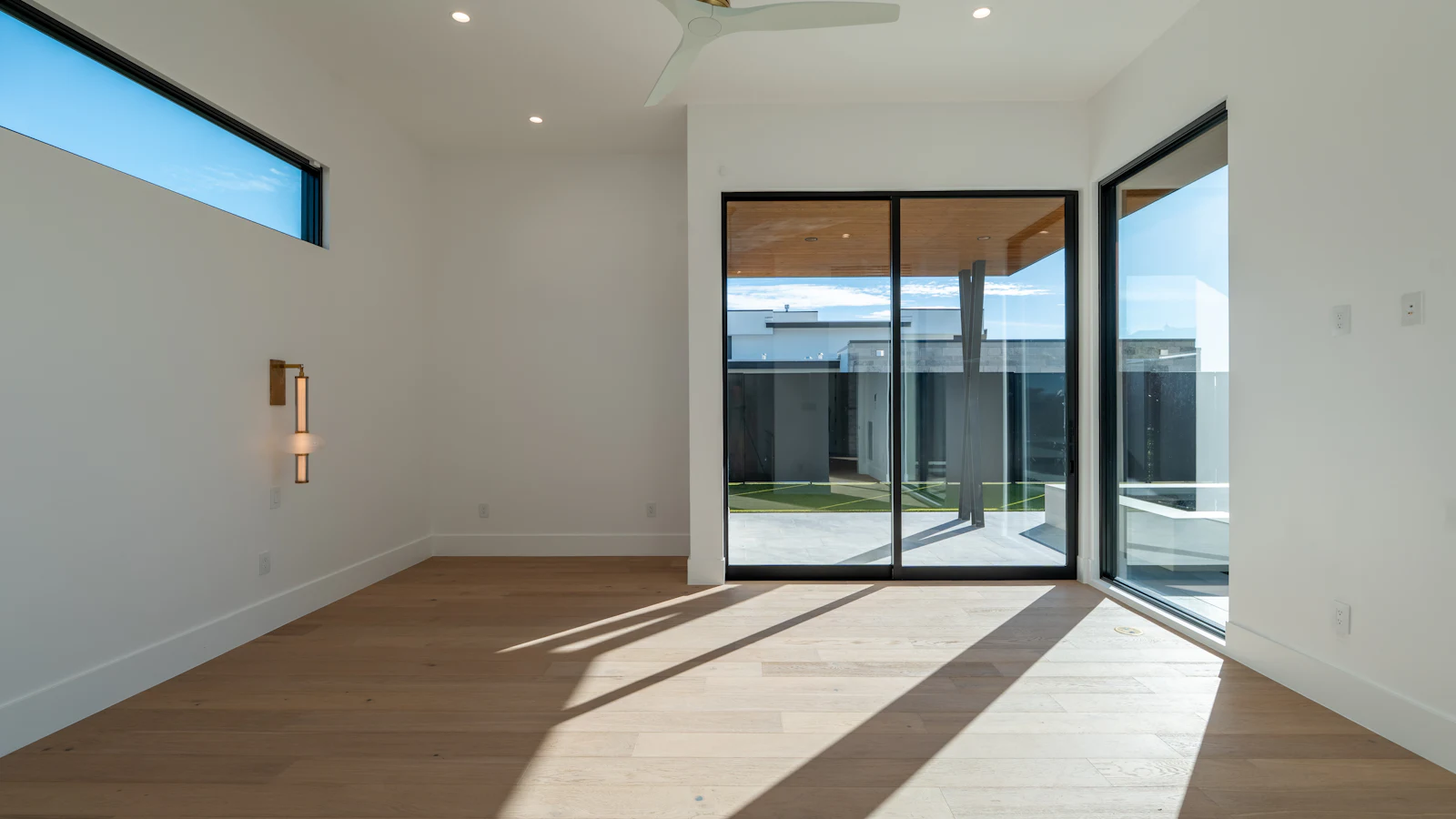 Bright modern room with light hardwood flooring and sunlight streaming through sliding glass doors