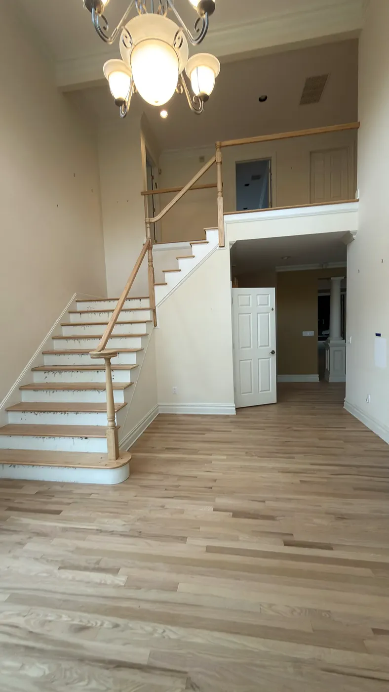 Two-story foyer staircase with wood handrail